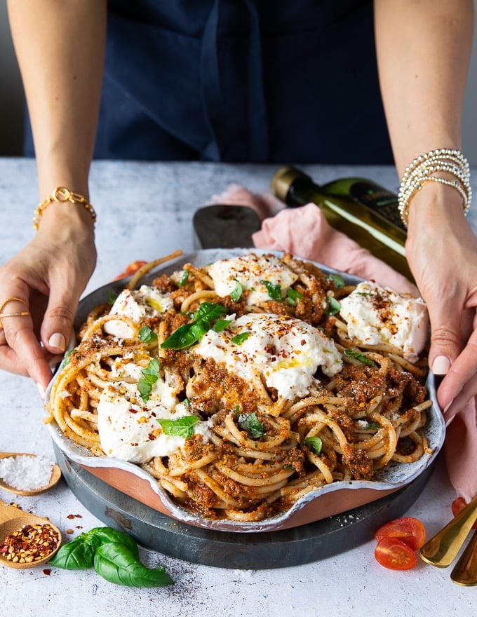 two hands holding a burrata pasta plate