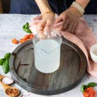 A hand holding a cup of pasta water