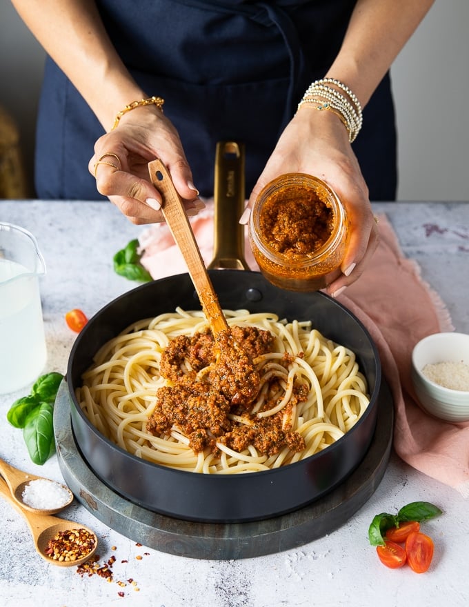 The cooked pasta drained and being tossed with sun dried tomato pesto