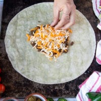 a hand adding cheese over the meat