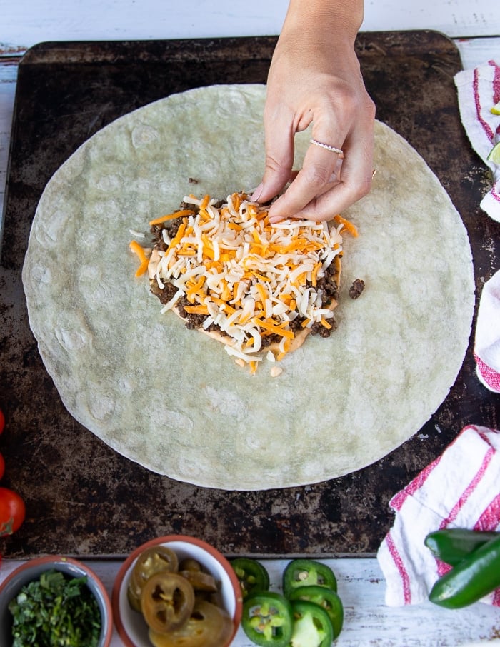 a hand adding cheese over the meat