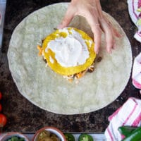 sour cream being spread over the tostada layer