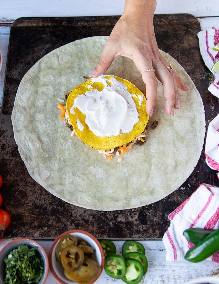 sour cream being spread over the tostada layer