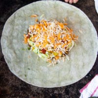 A big handful of shredded cheese is added over all the layers of the crunchwrap supereme