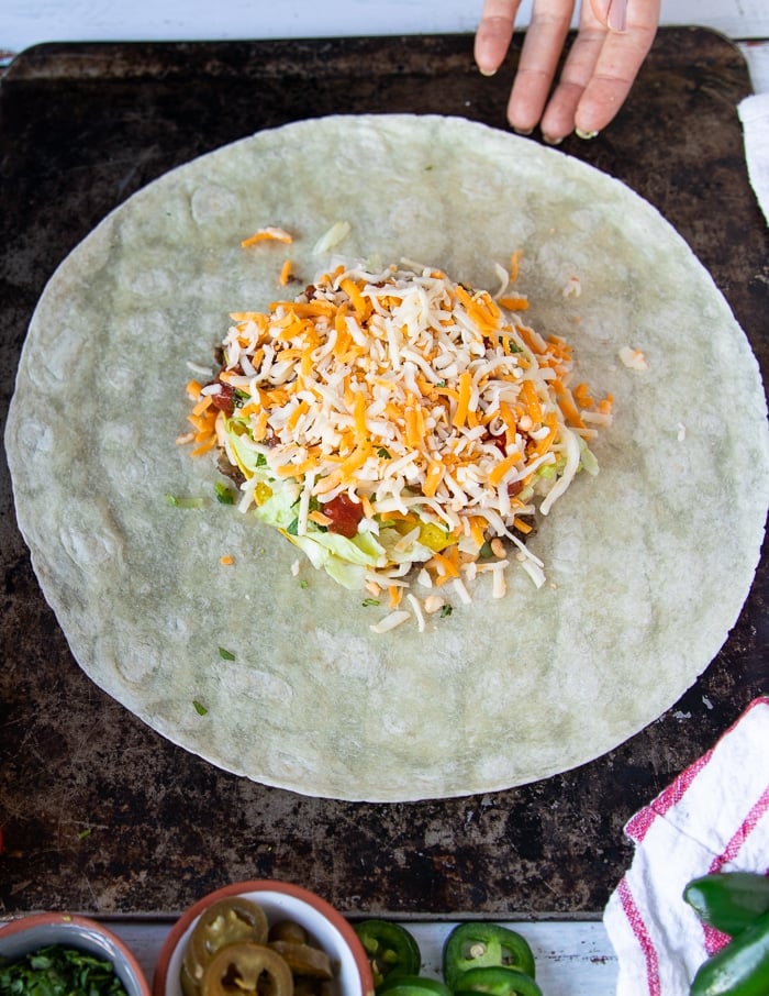 A big handful of shredded cheese is added over all the layers of the crunchwrap supereme