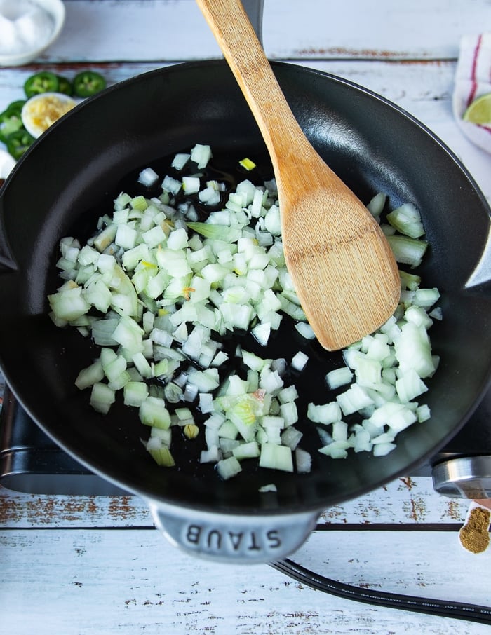 onions being cooked in oil over a medium high heat skillet until soft