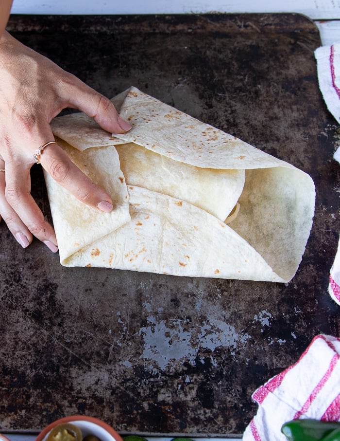 three sides folded over creating pleats and one hand holding them down firmly