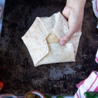 fully folded up crunchwrap supreme held tightly with one hand