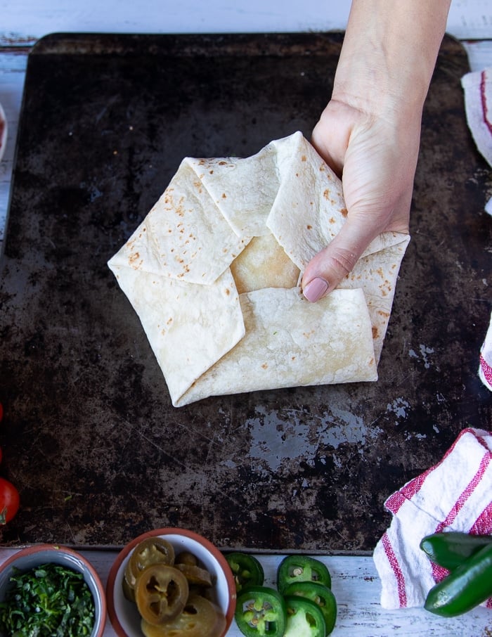 fully folded up crunchwrap supreme held tightly with one hand
