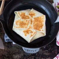 folded over crunchwrap supreme in the skillet showing the golden top