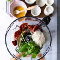 Ingredients for pesto in a food processor bowl.