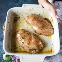 The chicken breasts placed in a plate all sprinkled with seasoning and olive oil