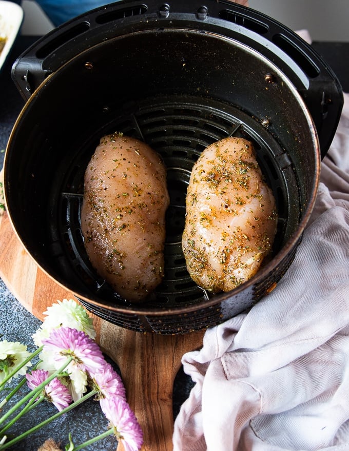 the chicken breasts placed in an air fryer basket and ready to cook