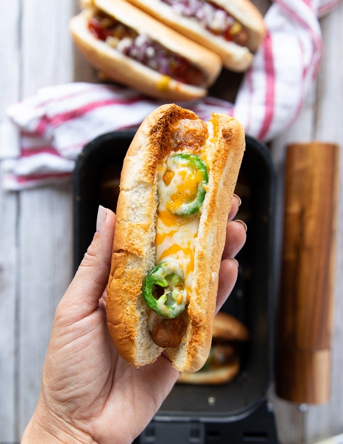 A hand holding a cheesy hot dog bun