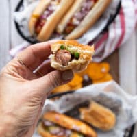 A hand holding a bitten off hot dog sandwich showing how juicy air fryer hot dogs are