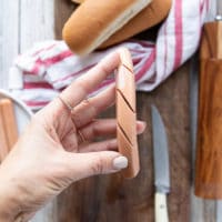 a hand holding the ready hot dogs with slits to go in the air fryer