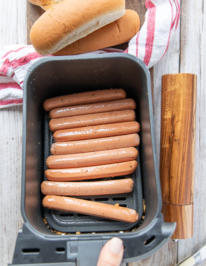 hot dogs arranged in an air fryer basket