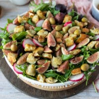 Remaining burrata salad ingredients are added to the salad plate including radishes, croutons, olives