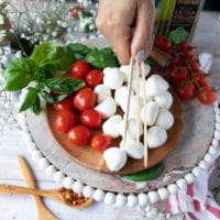 A hand holding wooden skewers for skewering the caprese skewers recipe