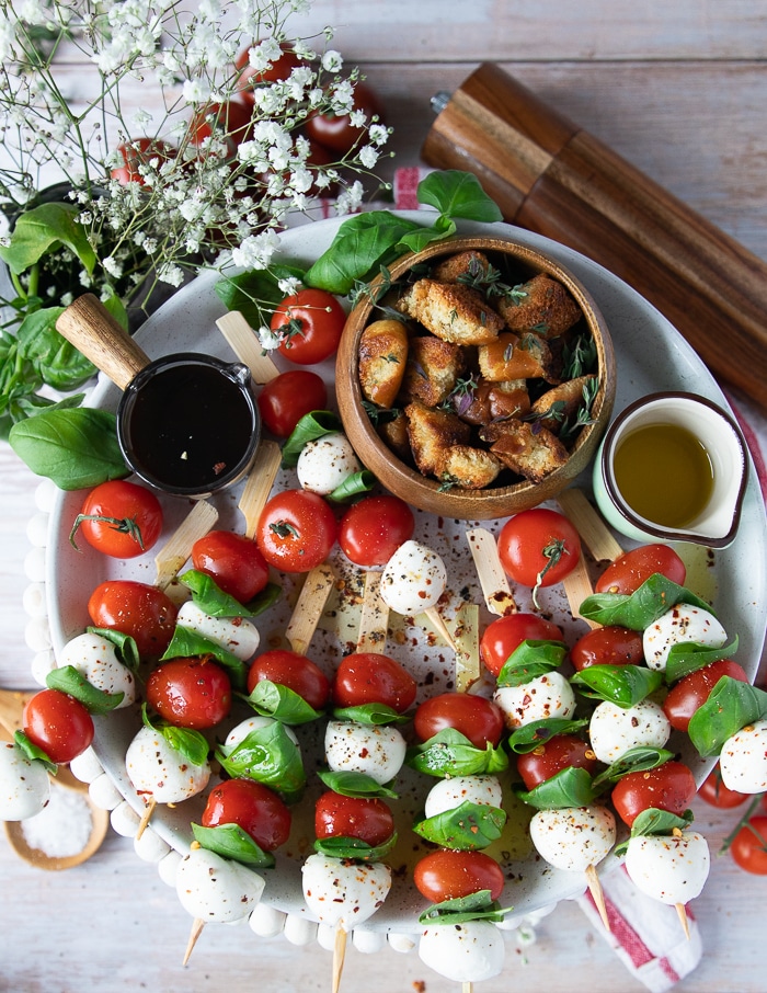 A plate of caprese salad in a skewer served with light seasoning