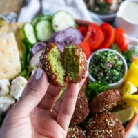 A hand holding a falafel bitten to show how crispy it is and how the inside is so flavorful