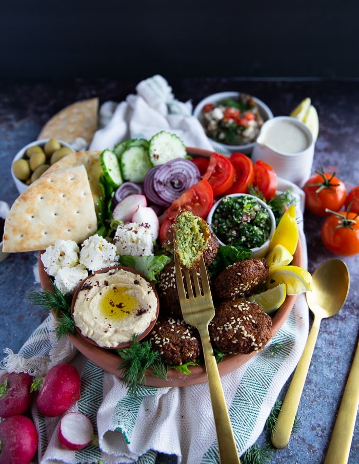 A fork eating the falafel salad bowl and holding on to a chunk of falafel 