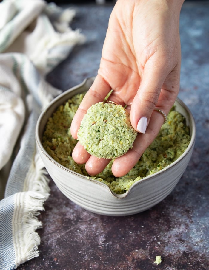 A hand shaping up the falafel mix into a round falafel shape ready to fry it