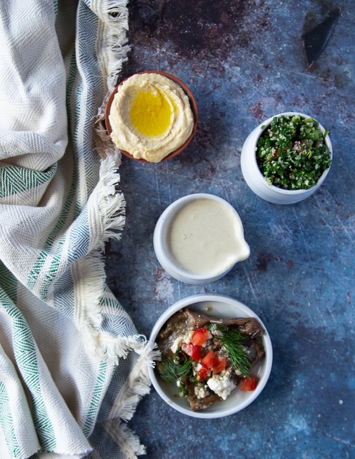 falafel bowl fixings such as tahini sauce, tabouleh, hummus dip and eggplant salad