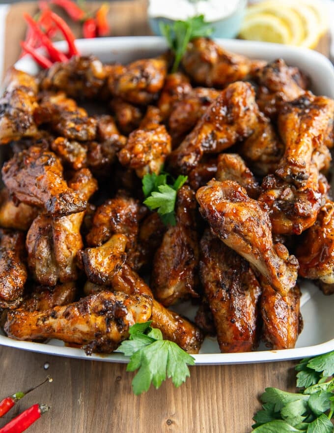 close up of grilled chicken wings showing the crispy skin and the sauces coating them 