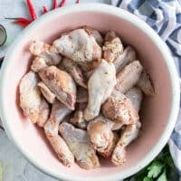 Chicken wings seasoned with spice blend and olive oil in a large bowl ready to grill
