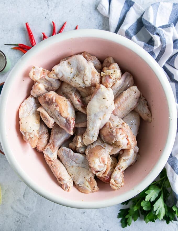 Chicken wings seasoned with spice blend and olive oil in a large bowl ready to grill