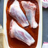 lamb shanks in a large dish marinating in the birria sauce