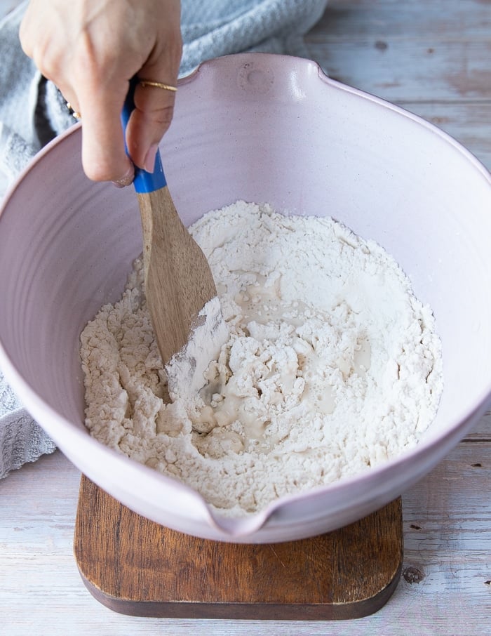 Mixing the pizza dough using a wooden spoon