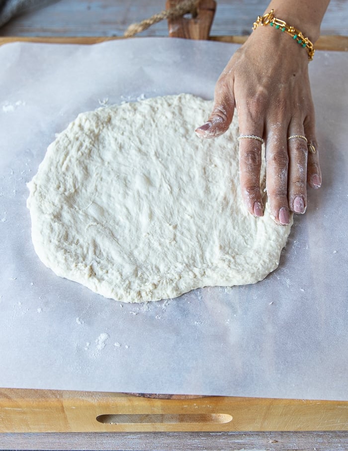 Stretching the no-knead pizza dough before baking.