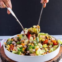 A hand with two spoons serving the taco salad