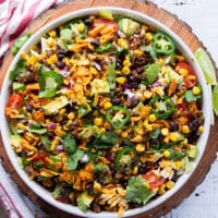 taco salad ingredients all tossed together in a large plate and ready for the dressing