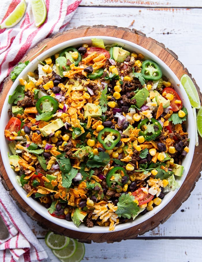 taco salad ingredients all tossed together in a large plate and ready for the dressing