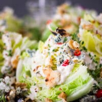 close up of a wedge salad dressed in blue cheese dressing and topped with croutons, chillies and seasoning