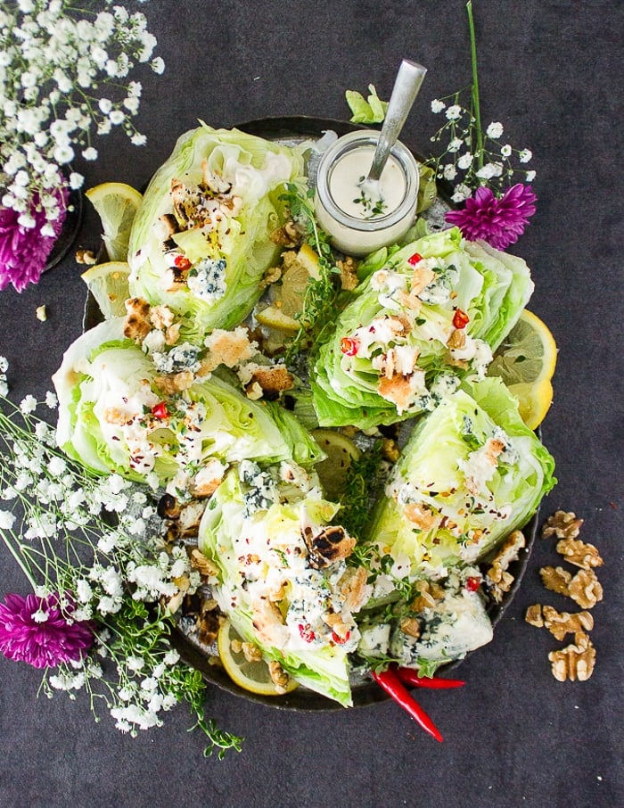 A full plate of wedge salads with blue cheese dressing and blue cheese crumbles and croutons