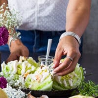 A hand adding crumbles of blue cheese over the wedge salad