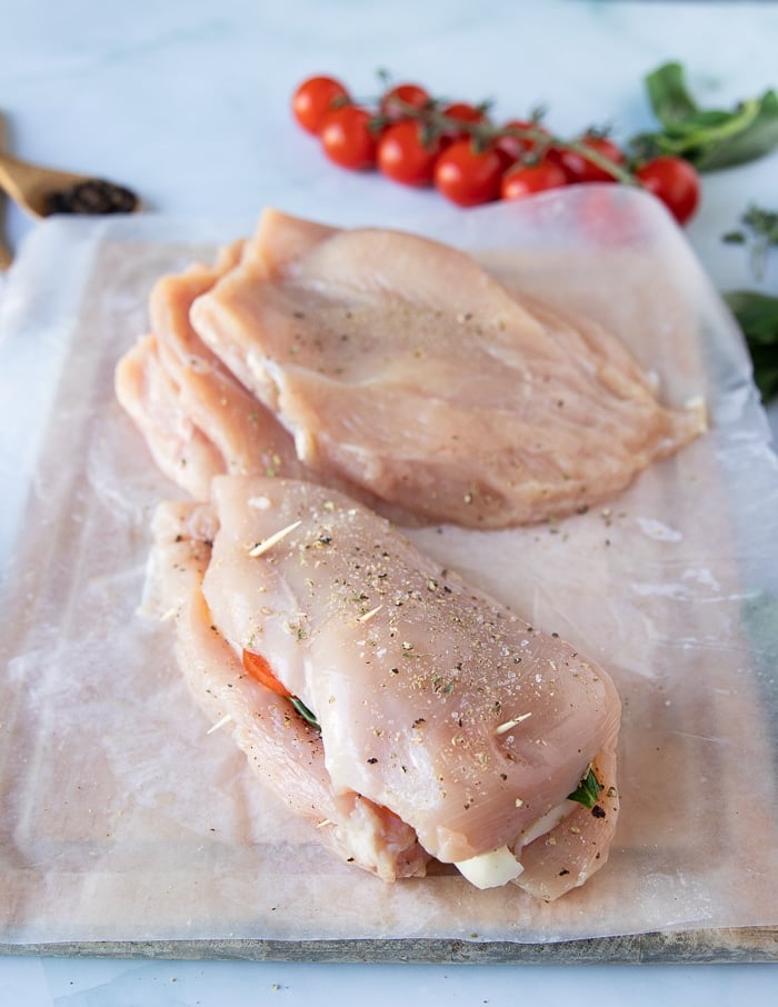 the chicken caprese is secured with toothpicks to seal in the filling