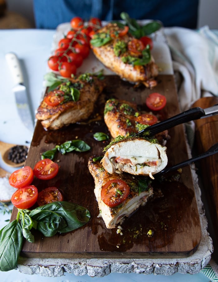 A hand holding a cut up piece of chicken caprese showing how juicy it is