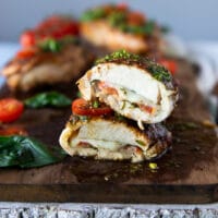 one cut up piece of chicken caprese stacked to show how cooked and juicy the chicken is and show the tomato, cheese and basil later close up