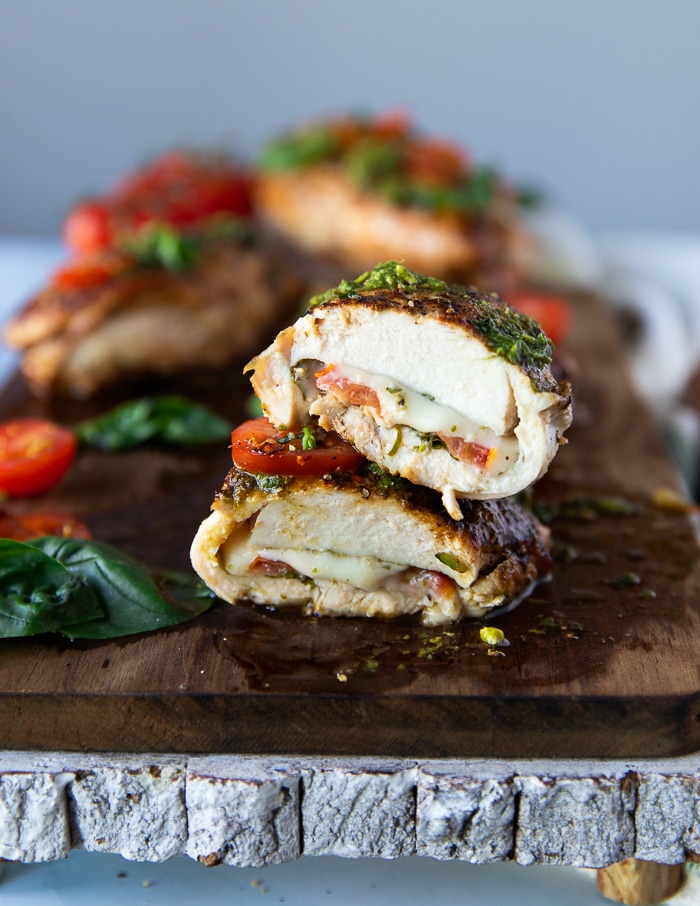 one cut up piece of chicken caprese stacked to show how cooked and juicy the chicken is and show the tomato, cheese and basil later close up