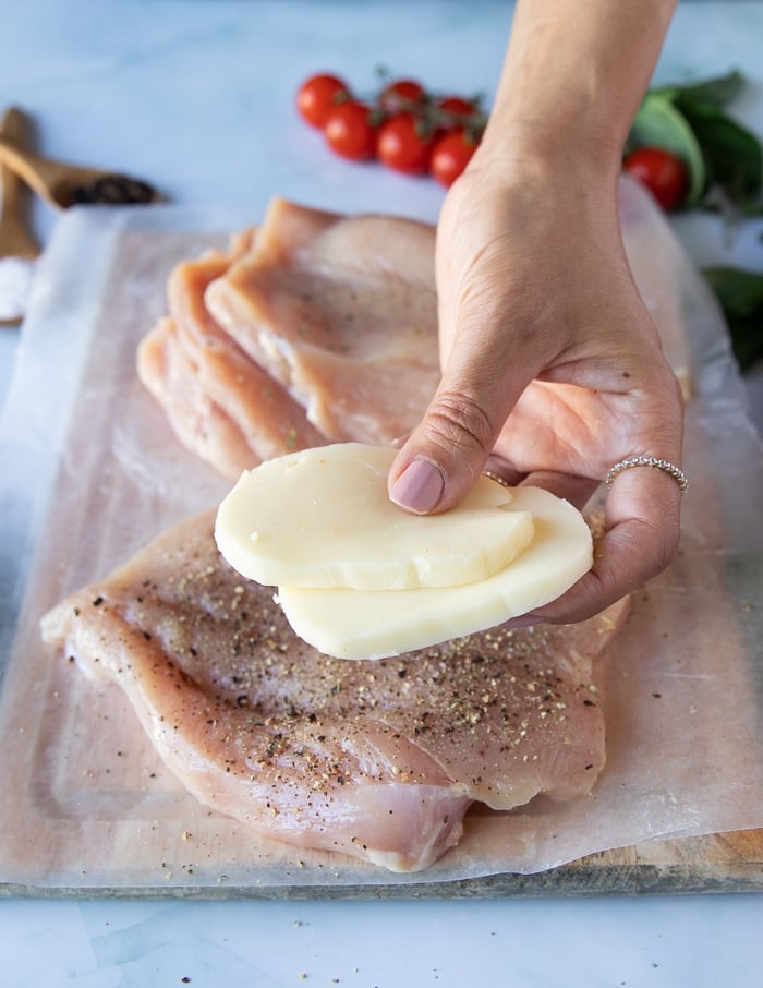 A hand holding two slices of fresh mozzarella cheese