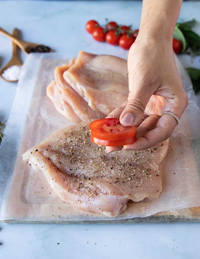 a hand holding three slices of tomatoes