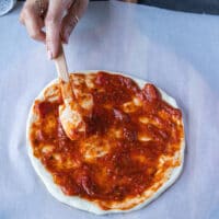 pizza dough spread with tomato sauce.