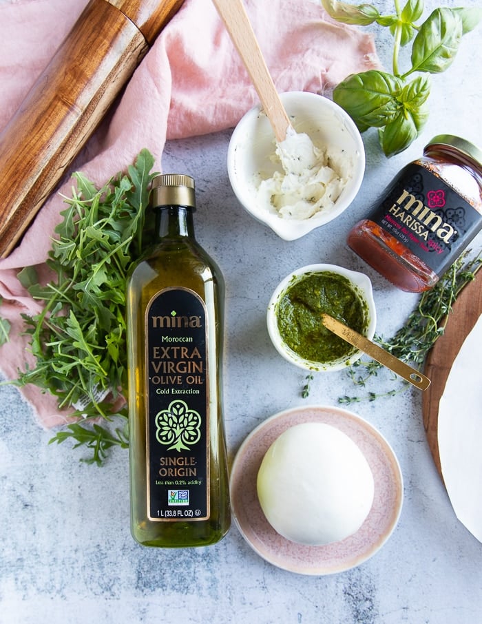 Burrata Pizza Ingredients: white sauce, olive oil, pesto, harissa, pizza dough, arugula.