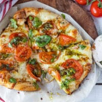 Finished Caprese Pizza on a wooden board.