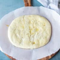 raw pizza dough on a piece of papers stretched and ready to use